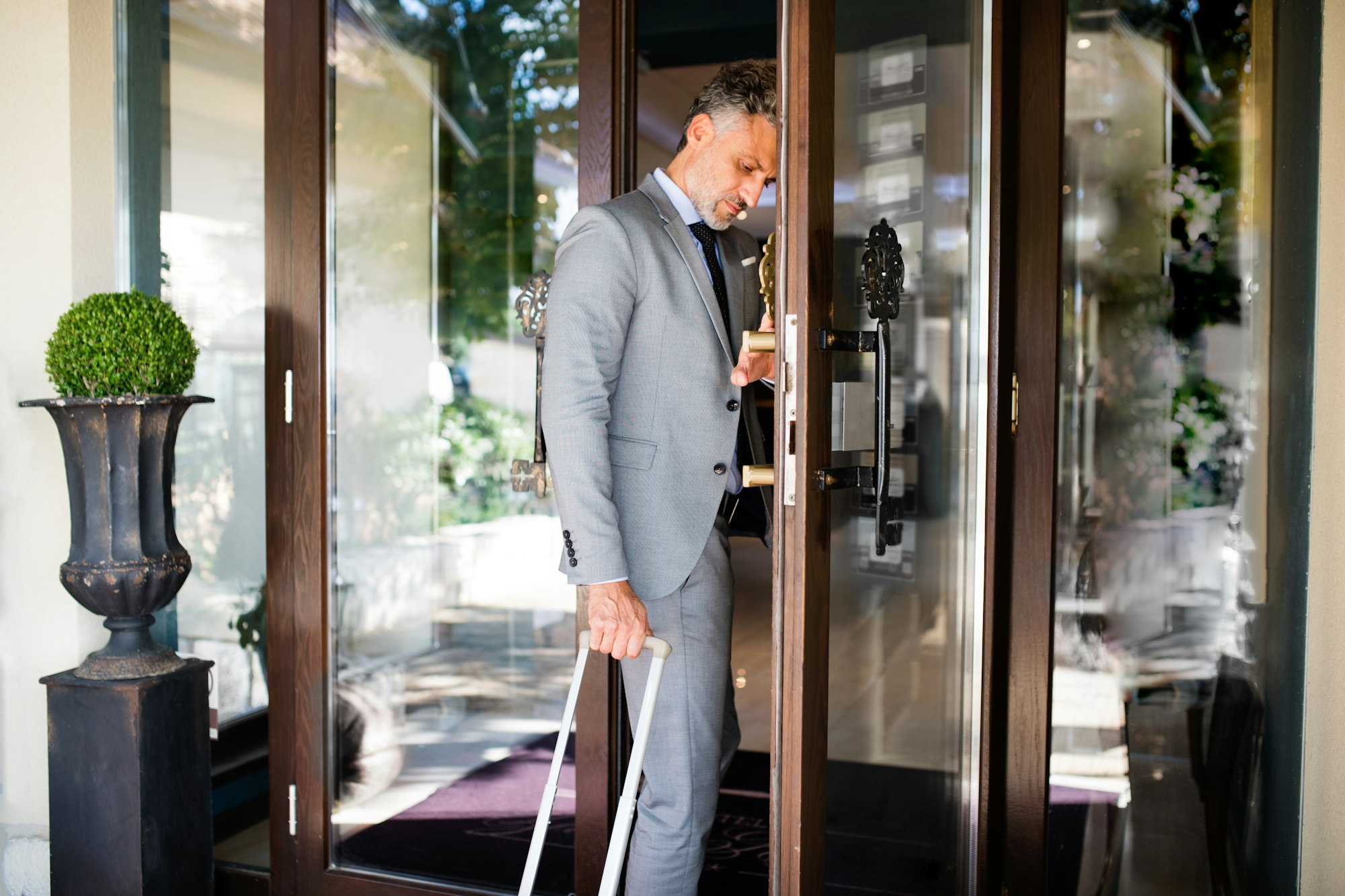 Mature businessman entering hotel with luggage.